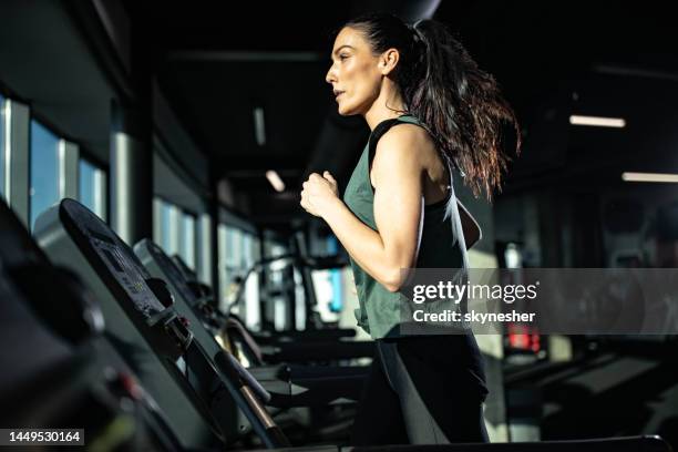 determined athletic woman running on treadmill in a gym. - treadmill stock pictures, royalty-free photos & images