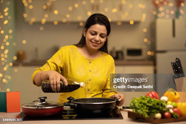 portrait of indian woman enjoying while cooking meal in the kitchen. stock photo - woman cooking stock pictures, royalty-free photos & images