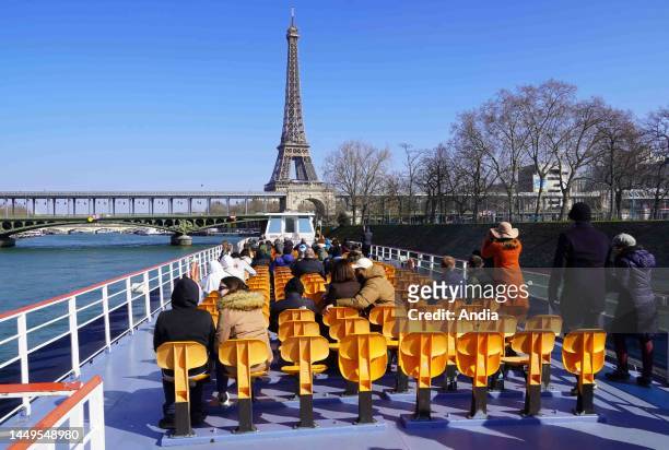 Tourist on an excursion boat of the Bateaux Mouches company in winter, admiring the Eiffel Tower and the Bir-Hakeim Bridge in the 15th arrondissement...