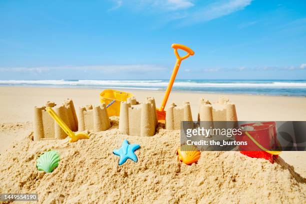 large sand castle and colorful toys at beach and sea against sky - beach bucket stock pictures, royalty-free photos & images