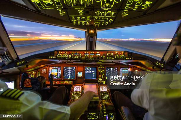 Airliner cockpit with a pilot and a co-pilot and runway viewed from the interior at night.
