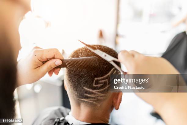 理髪師は、はさみを保持するクライアントの髪にデザインを剃る - hairstyle ストックフォトと画像