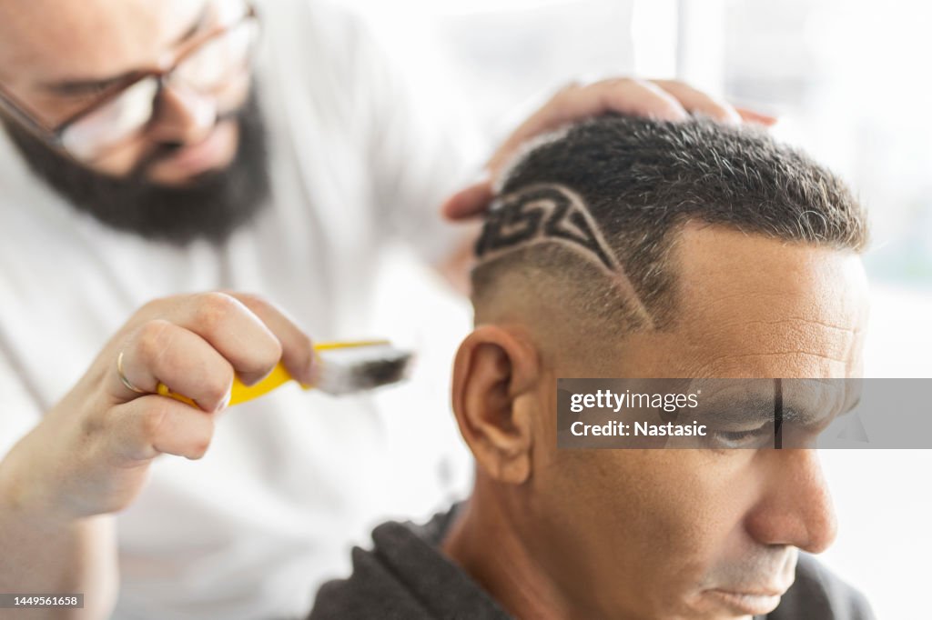 Barber brushing designs shaved on a clients hair