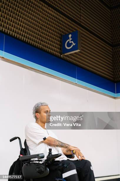 portrait of latin american student men on wheelchair waiting on subway platform with backpack - fauteuil handicap stock pictures, royalty-free photos & images