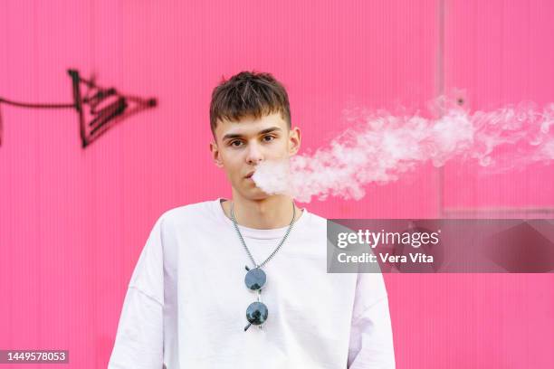 portrait of skater hispanic man with urban style smoking outdoors. - electronic cigarette stockfoto's en -beelden