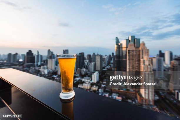 glass of beer at the luxury hotel rooftop bar in bangkok, thailand - bar table ストックフォトと画像