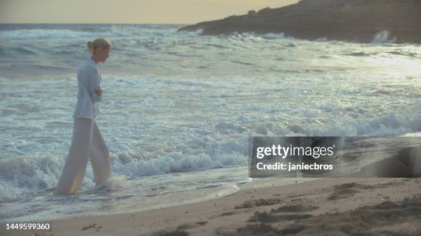 woman walking alone on a beach. looking off into distant sea enjoying the wind - i miss you stock pictures, royalty-free photos & images