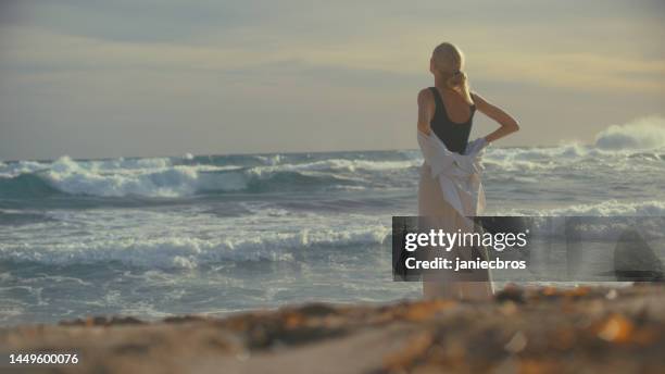 woman standing alone on a beachside cliffs. looking off into distant sea - i miss you stock pictures, royalty-free photos & images