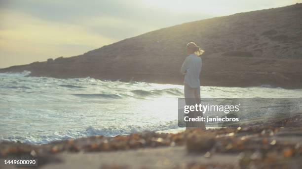 woman walking alone on a beachside cliffs. looking off into distant sea enjoying the wind - i miss you stock pictures, royalty-free photos & images