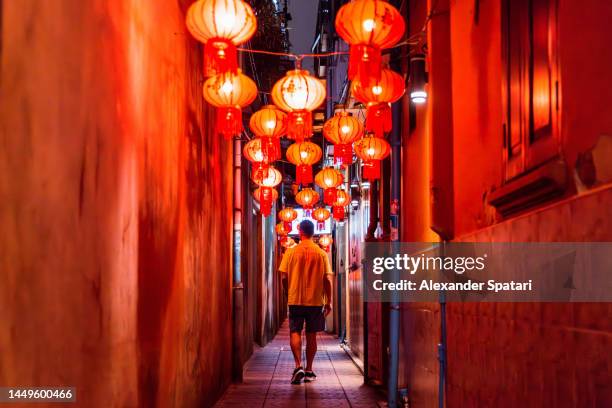 man walking through a narrow alley decorated with chinese lanterns at night, bangkok, thailand - adventure club stockfoto's en -beelden