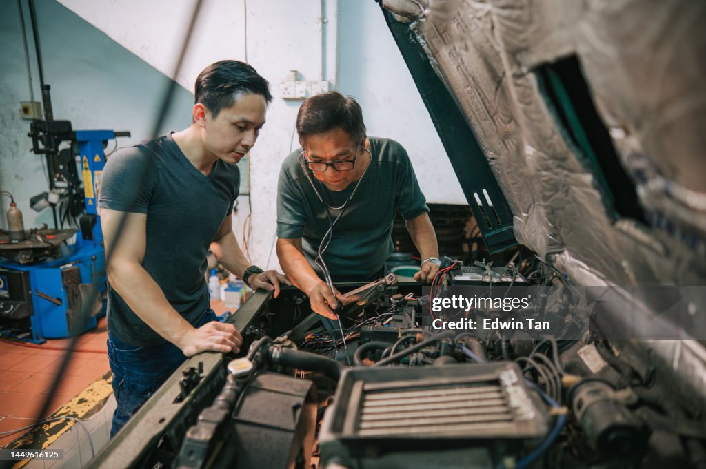 Meccanico senior cinese asiatico che mostra la diagnosi dei rumori del motore dell'automobile di un collega