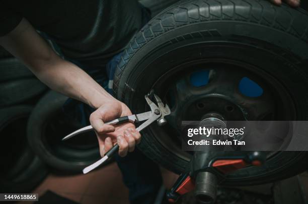 自動車修理店でタイヤを修理するアジアの中国人メカニックの接写 - wheel rim ストックフォトと画像