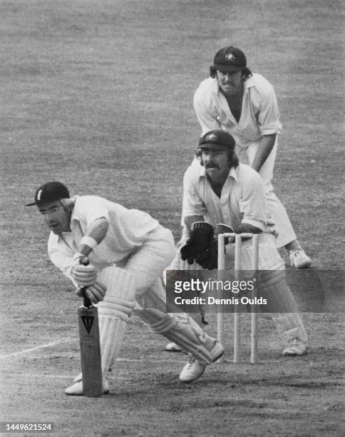 Australian wicketkeeper Rodney Marsh and team captain Ian Chappell look on from behind the stumps as England batsman David Steele plays a forward...