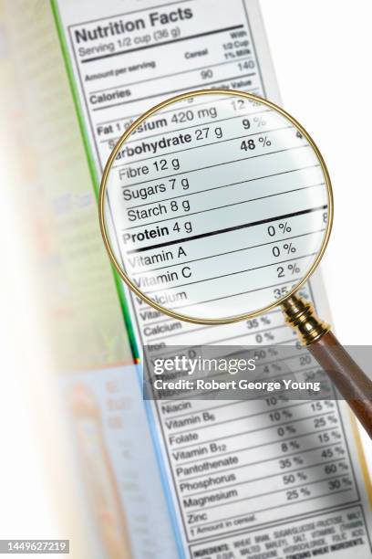 magnifying glass examining nutritional data on a box of food - nutritional information stock pictures, royalty-free photos & images