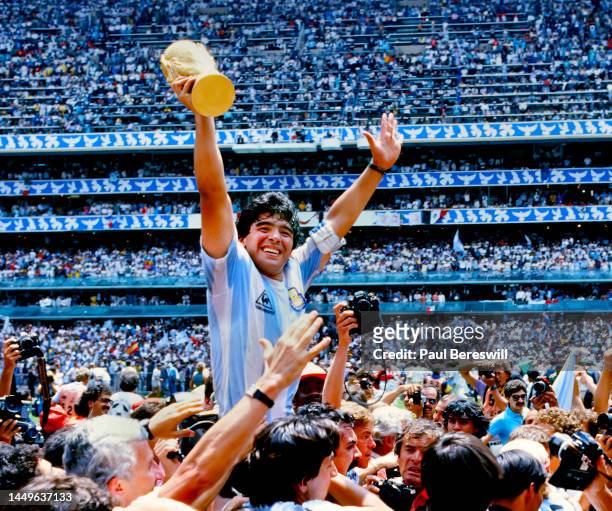 Diego Maradona of Argentina, hoists the FIFA World Cup trophy, celebrating as he is carried off the field by fans and teammates after the 1986 FIFA...