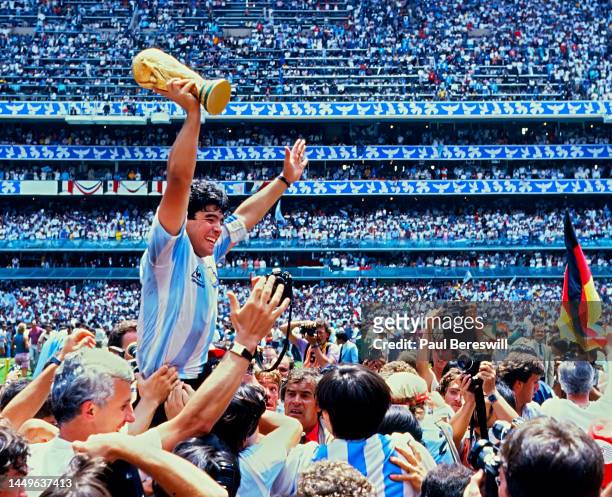 Diego Maradona of Argentina, hoists the FIFA World Cup trophy, celebrating as he is carried off the field by fans and teammates after the 1986 FIFA...