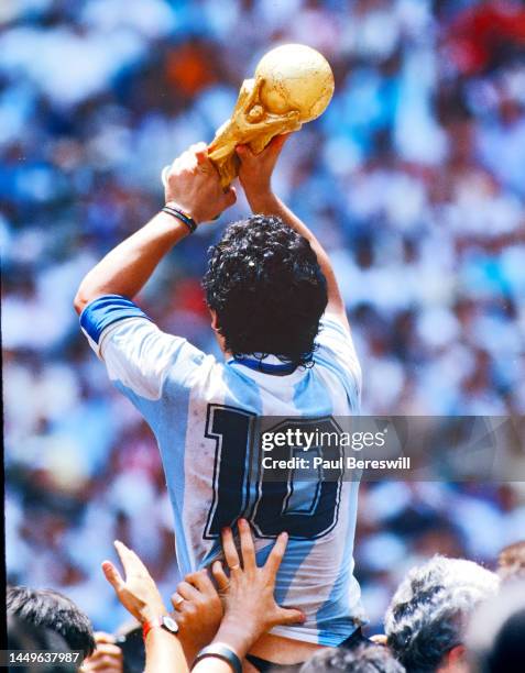 Diego Maradona of Argentina, hoists the FIFA World Cup trophy, celebrating as he is carried off the field by fans and teammates after the 1986 FIFA...