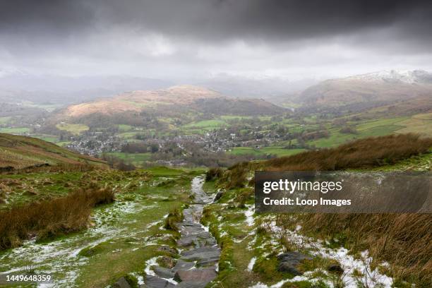 The view west from Wansfell over Ambleside, Loughrigg Fell and the snow-capped Cumbrian mountains beyond in the Lake District National Park.