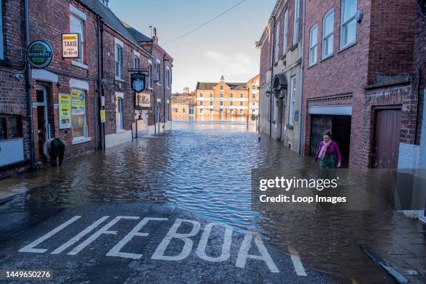 Woman makes her way through a flooded street as large areas by the river Ouse in the centre of York are flooded after heavy rains.