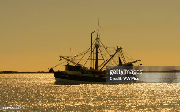 Commercial shrimp boat heads out to see through the Brownsville Ship Channel by South Padre Island, Texas.