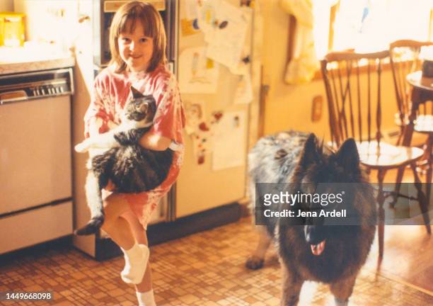 vintage child with cat and dog, 1990s family pets indoors, longhair german shepherd - girls cuddling cat stock-fotos und bilder
