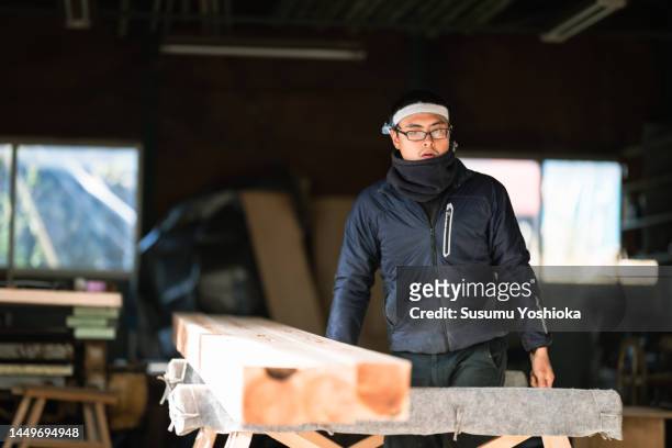 young carpenter processing materials for wooden house construction. - buff photos et images de collection