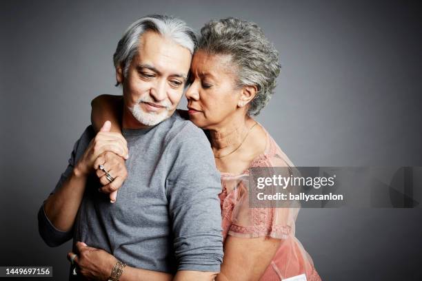 studio portrait of a senior hispanic man and senior african american woman embracing. - couples studio portrait stock pictures, royalty-free photos & images