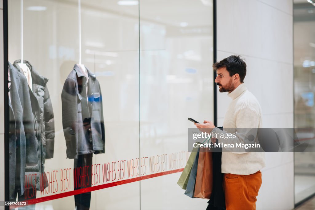 Handsome young man window shopping in a mall