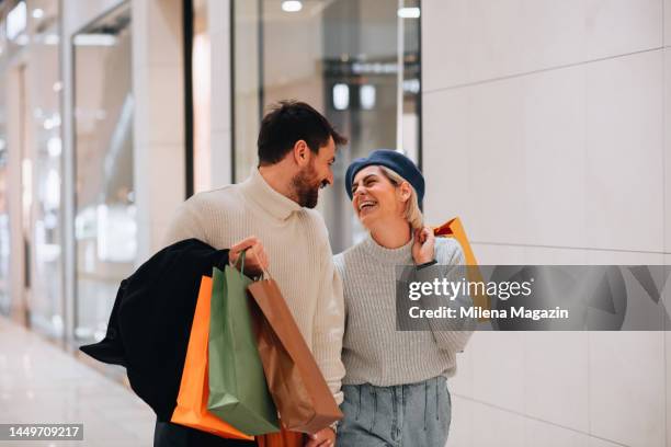 paar glücklich nach einem einkaufsbummel, hält taschen voller geschenke und lächelt - shopping spree stock-fotos und bilder