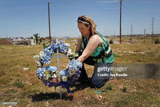 Angela Baumann sets up a cross on the site where her best friend's home was before the tornado tore it apart and killed Malisa Crossley almost one...