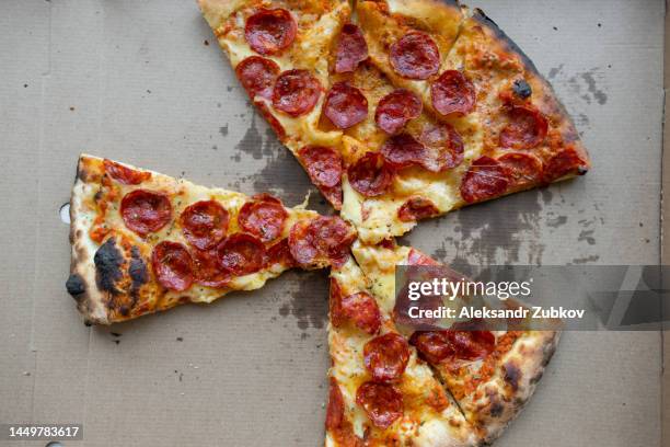 delicious italian pizza in a pizza box and a delivery box, on the table in a pizzeria. sliced pizza slice with tomatoes, pepperoni sausage and cheese. the concept of unhealthy lifestyle, overeating, junk food, fast food. delivery to your home or work. - pizza slice stock pictures, royalty-free photos & images