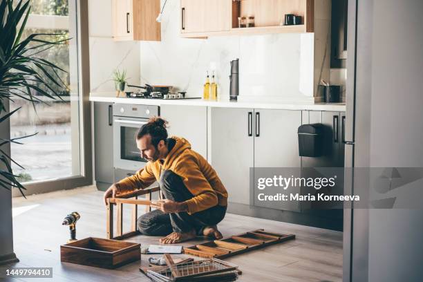 man assembling furniture at home. - heimwerker stock-fotos und bilder