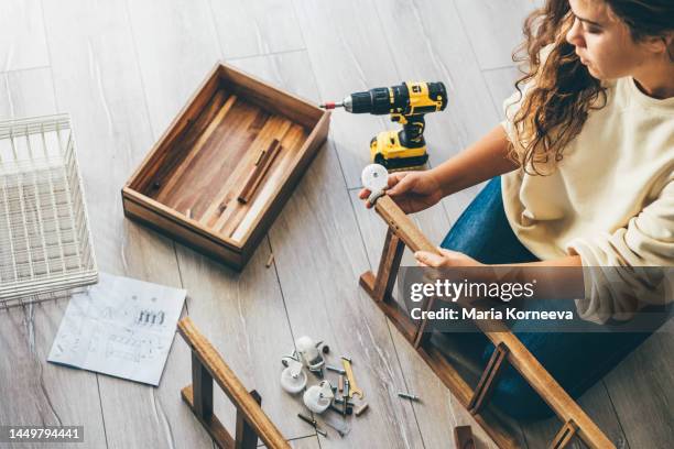 woman assembling furniture at home. - furniture maker foto e immagini stock