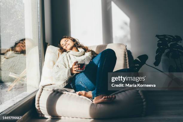 cheerful young woman enjoying tea and relaxing at the sofa in the morning. - intérieur bus de voyage photos et images de collection