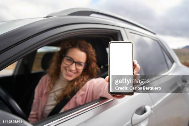 lady showing phone while sitting inside new car. - auto display stock-fotos und bilder