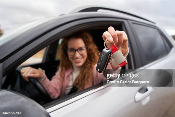 smiley woman showing car keys to camera while sitting inside her new vehicle. - selective focus imagens e fotografias de stock