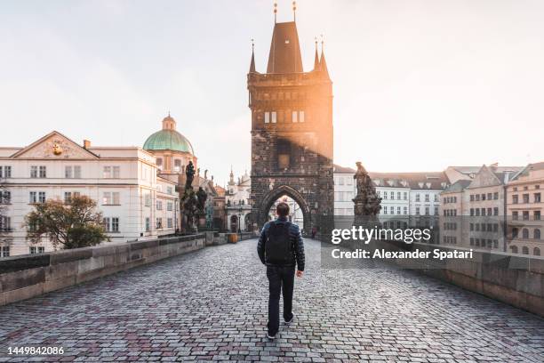 rear view of a man walking on the charles bridge in prague, czech republic - prague photos et images de collection