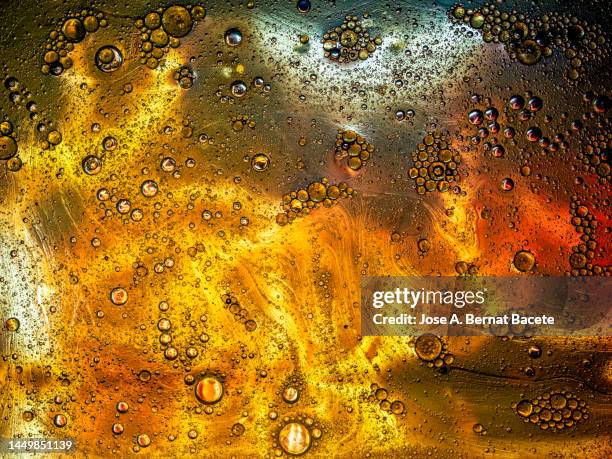 full frame of gold colored liquid bubbles floating on a metal surface. - eukaryote stock pictures, royalty-free photos & images
