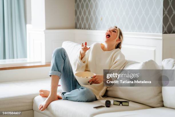 tricks with popcorn, trying to catch. woman eating popcorn and watching tv at home - mundraum stock-fotos und bilder