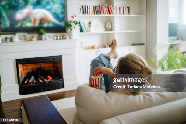 animals and nature channels on streaming service or tv set. woman in eyeglasses eating popcorn and watching tv at home - apple tv - fotografias e filmes do acervo