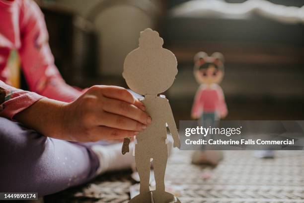 a little girl plays with cardboard cut-outs of a fashion doll - dolls stock-fotos und bilder