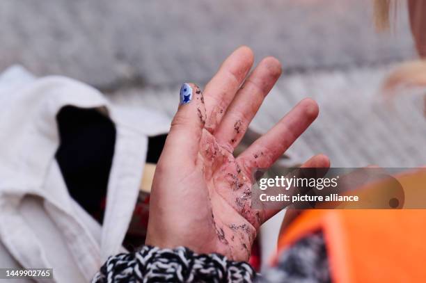 The hand of an activist of the climate protection group Letzte Generation is red from the glue and dirty from the asphalt. Last Generation protests...