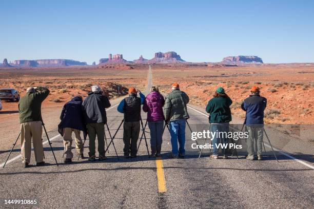 Group of photographers in a photo workshop taking pictures of the road to Monument Valley on the Utah-Arizona border. Note: a spotter was watching...