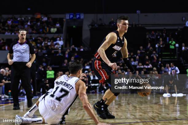 Tyler Herro of the Miami Heat dribbles the ball against Doug McDermott of the San Antonio Spurs during the game between San Antonio Spurs against...