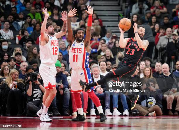 Fred VanVleet of the Toronto Raptors passes the ball off against Kyrie Irving and Joe Harris of the Brooklyn Nets during the first half of their...
