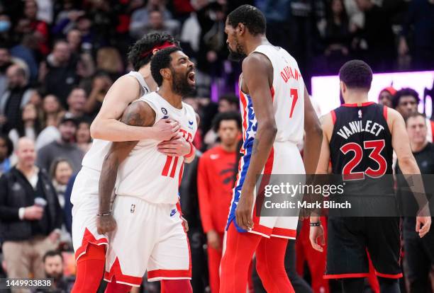 Kyrie Irving of the Brooklyn Nets celebrates his buzzer beater game winning shot with Kevin Durant and Yuta Watanabe against the Toronto Raptors...