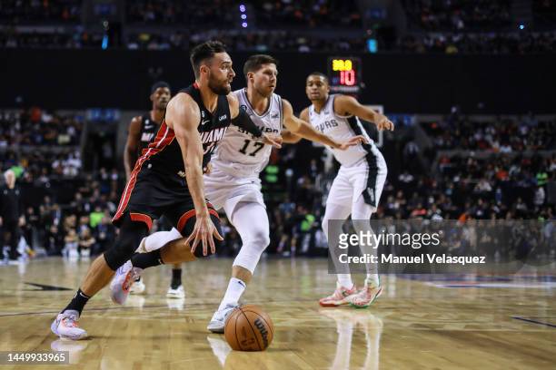 Max Strus of the Miami Heat dribbles the ball against Doug McDermott of the San Antonio Spurs during the game between San Antonio Spurs against Miami...
