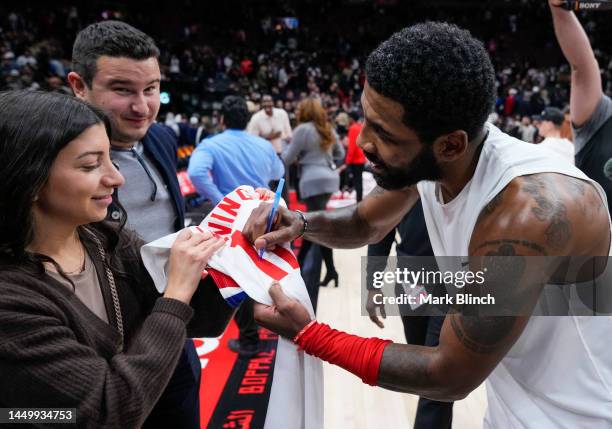 Kyrie Irving of the Brooklyn Nets signs a game worn jersey he wore while making the game winning buzzer beater shot against the Toronto Raptors in...