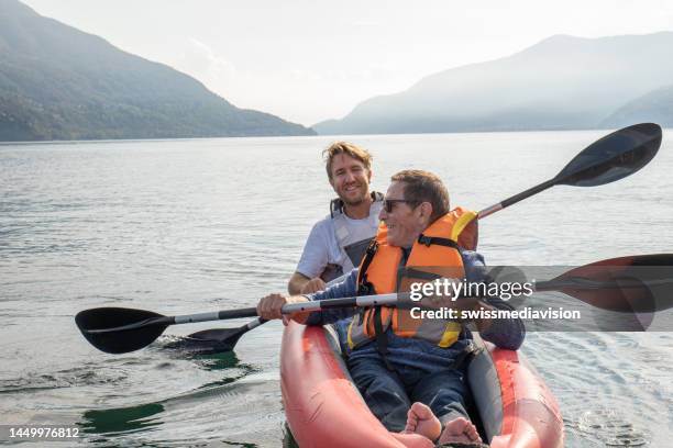 father and son canoeing on tranquil lake - seniors canoeing stock pictures, royalty-free photos & images
