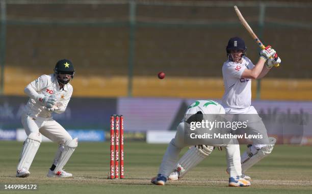 Harry Brook of England hits the ball past Abdullah Shafique of Pakistan, as Mohammad Rizwan of Pakistan watches on during Day Two of the Third Test...